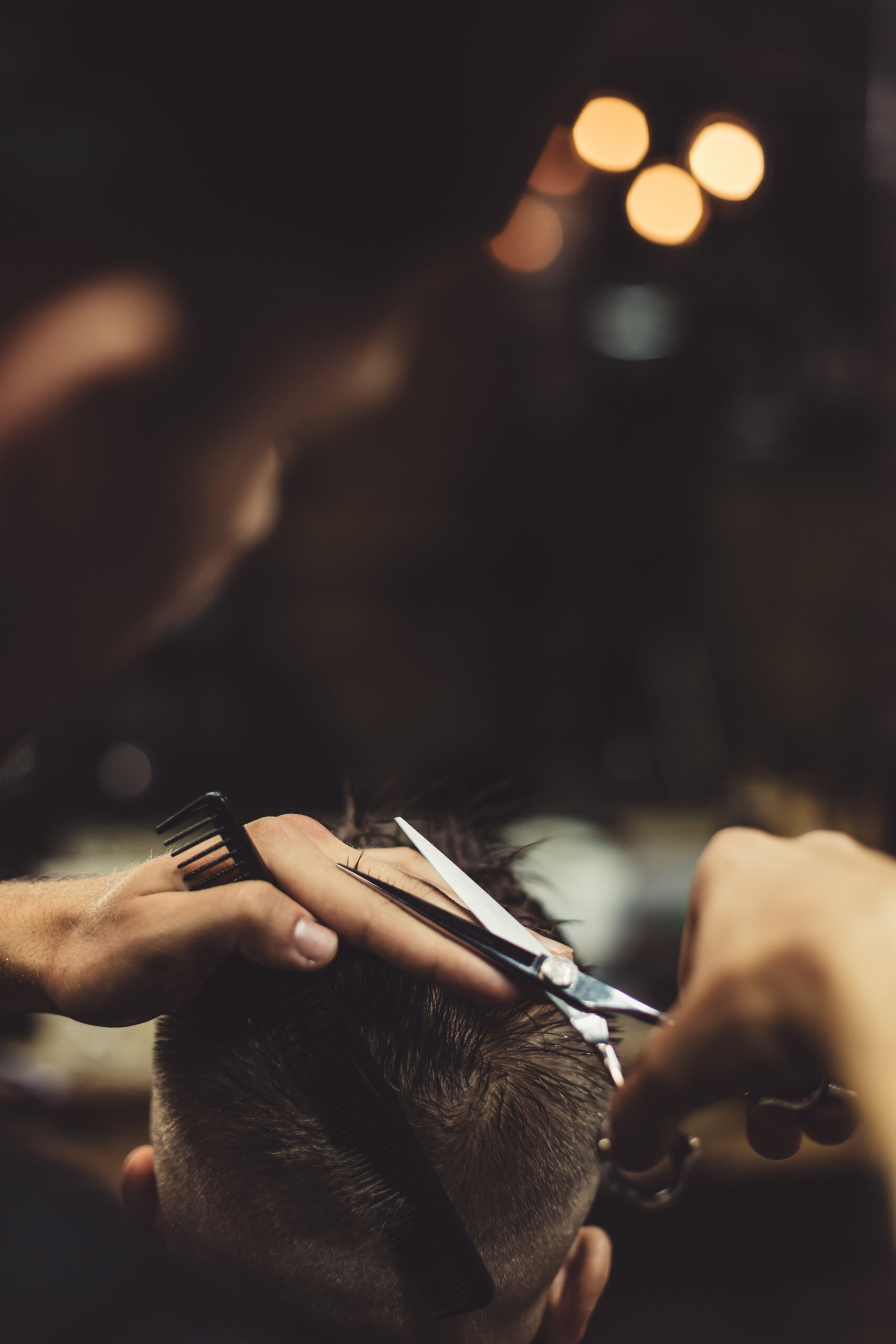 anonymous-stylish-barber-with-tattoos-cutting-hair-male-client-chair-scaled.jpg